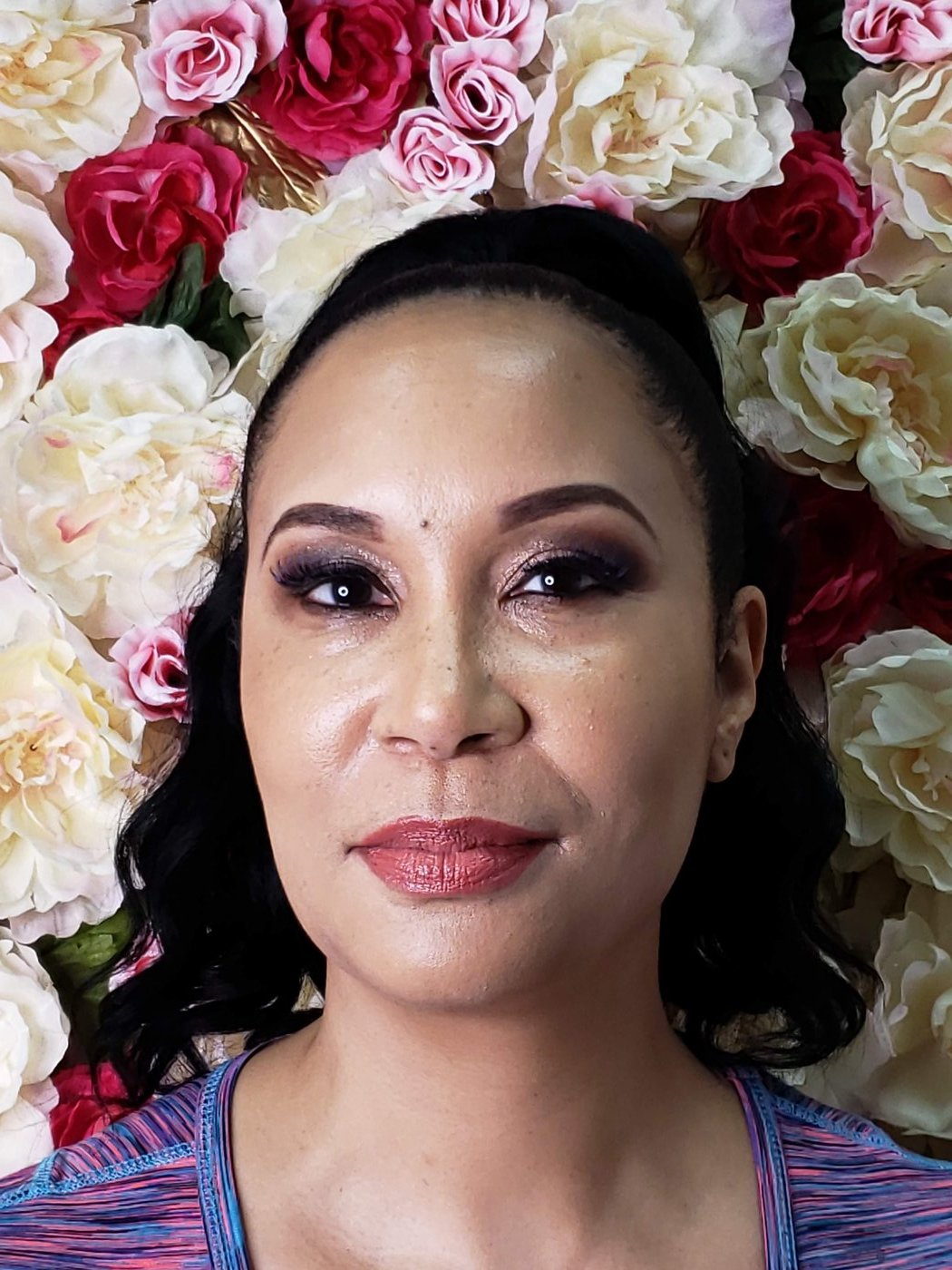 A finished makeup look in front of the studio's floral wall